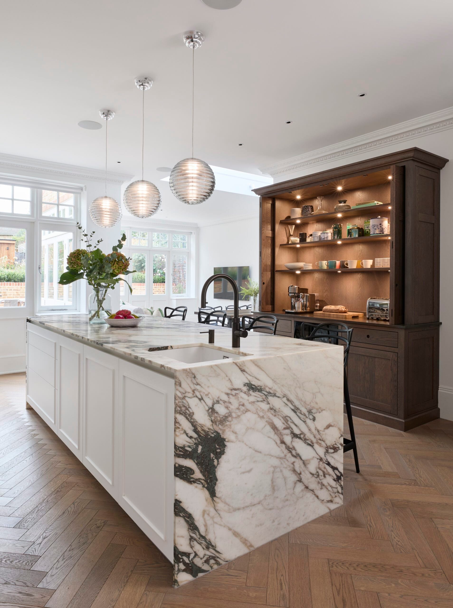 White marble island with dark oak breakfast pantry beyond at Victoria Road